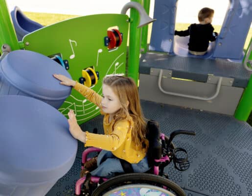 車いすに乗った女の子が音が出る遊具で遊んでいる様子