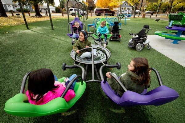 高い背もたれの座席を採用したインクルーシブシーソーで遊ぶ子どもたち